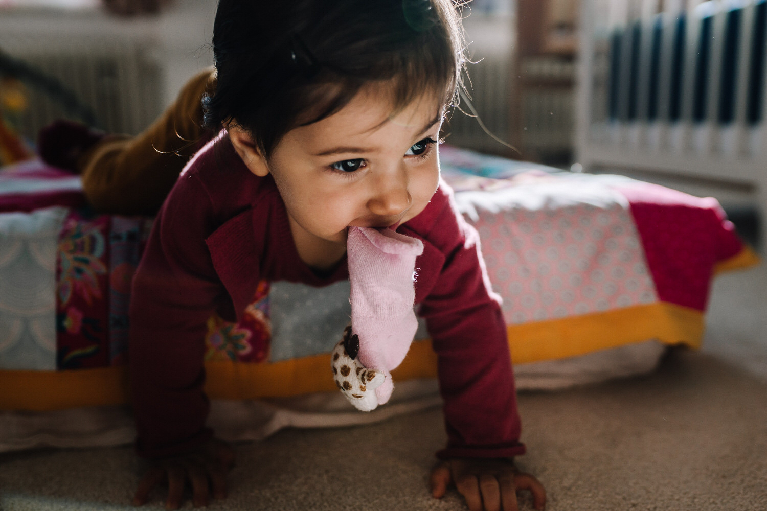 krabbelndes Kleinkind mit Socken im Mund dokumentarische Familienfotografie Aachen